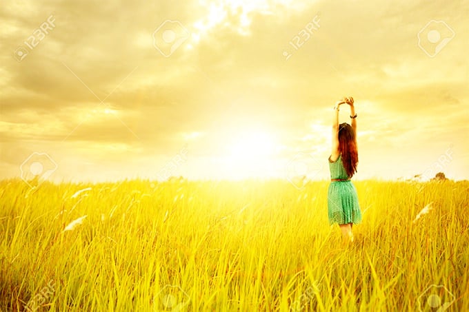 happy young asian woman standing in meadows with sunset